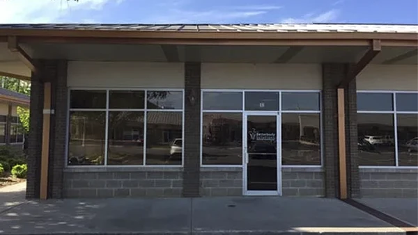 Exterior view of a clinic with large front windows, brick accents, and a single glass entrance door.